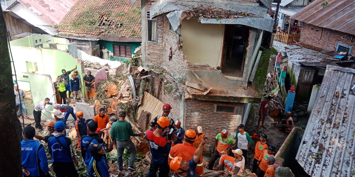 HANCUR: Warga dibantu relawan mengevakuasi sebuah pohon beringin yang tunbang dan menimpa beberapa rumah milik warga di Magelang. (Foto: Miftakhul Hayu Jatiningtias)