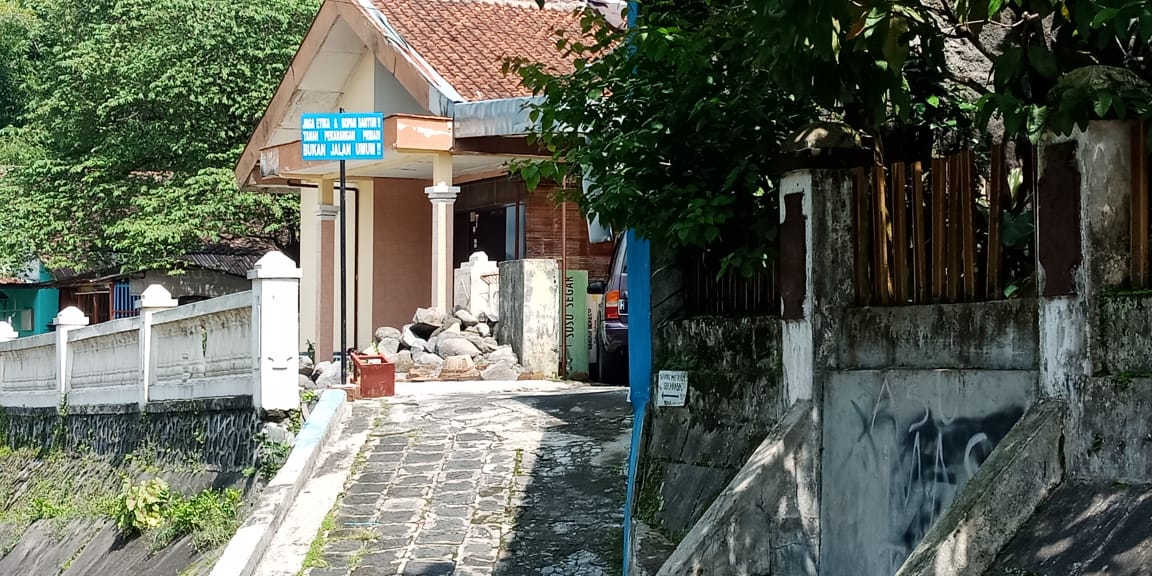 DIBLOKIR: Sudah tiga bulan lebih jalan yang sering digunakan warga dibolkir dengan timbunan material bangunan. (Foto: Miftakhul Hayu Jatiningtias)