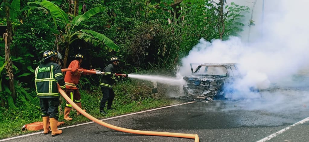 SEMPROT: Petugas Pemadam Kebakaran berupaya menjikakkan api yang melahap mobil di perbatasan Purworejo-Magelang, Sabtu (8/2). (Foto: Istimewa)