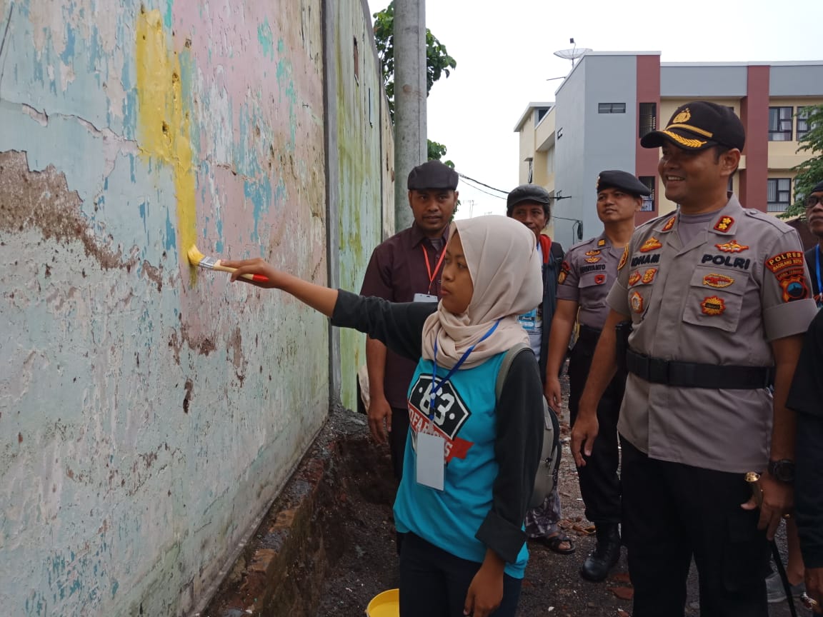 SIMBOLIS: Kapolres Magelang Kota AKBP Idham Mahdi (kanan) bersama seniman mural perempuan yang melakukan pewarnaan perdana pada dinding. (Miftakhul Hayu Jatiningtias)