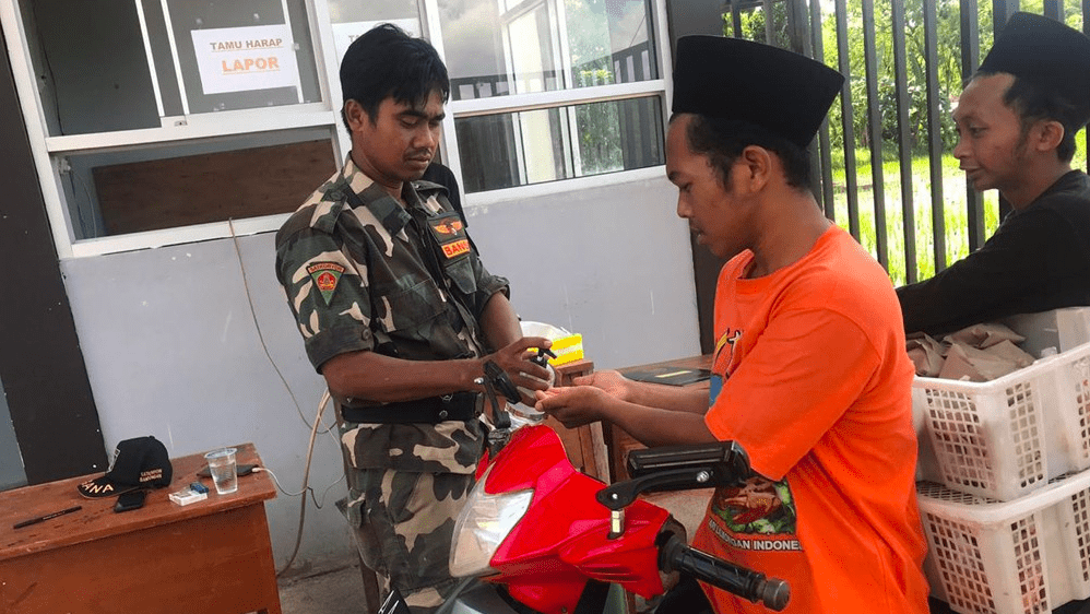 STERILISASI: Anggota Banser menyemprotkan hand sanitizer kepada santri yang memasuki pondok. (Sumber: NU Online)