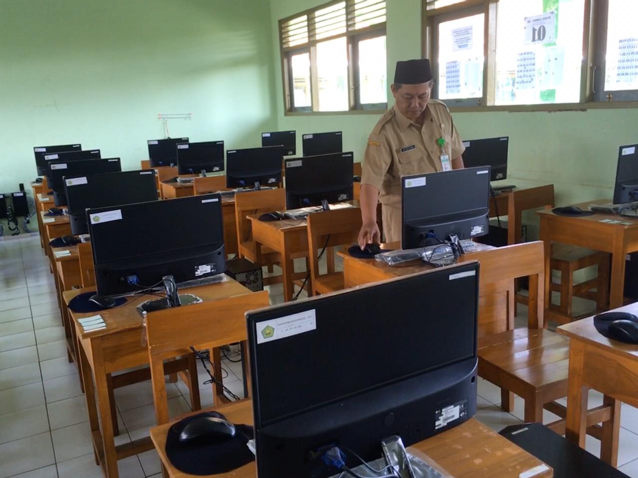 RUANG UJIAN: Kepala MTs Negeri 1 Magelang Gunartomo saat mengecek perangkat komputer untuk UAMBN BK, Senin (16/3). (Foto: han)