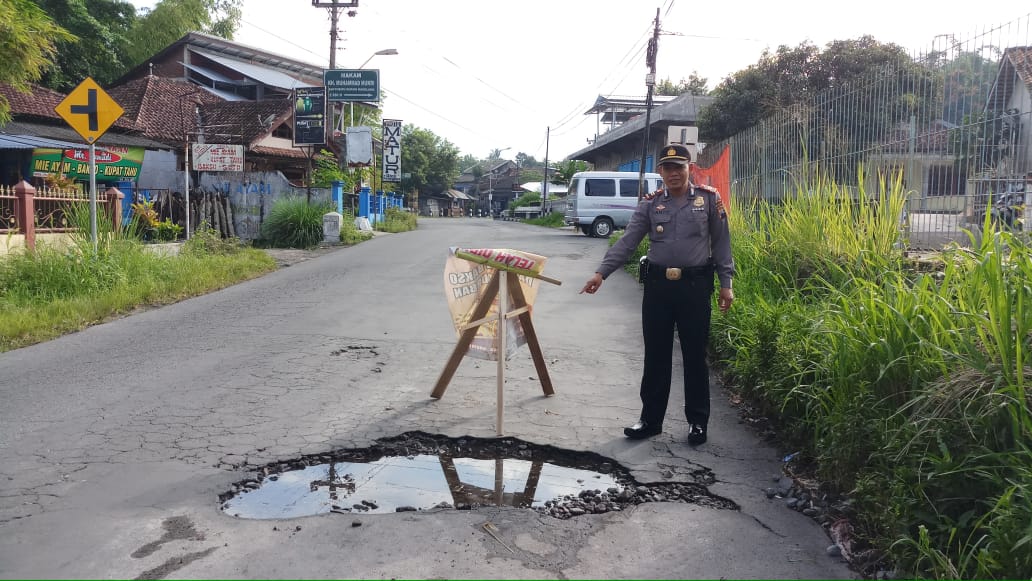 NEWS: PS Kapolsek Dukun IPTU Suyanto saat menunjukan jalan berlubang sebelum ditambal (19/3/2020)-(Foto: Istimewa)