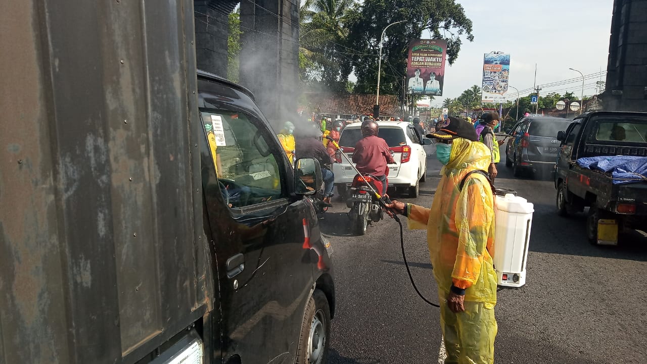 NEWS: Salah satu petugas menyemprotkan cairan desinfektan kepada kendaraan yang melintas perbatasan Magelang (21/3/2020)-(Foto: Istimewa)