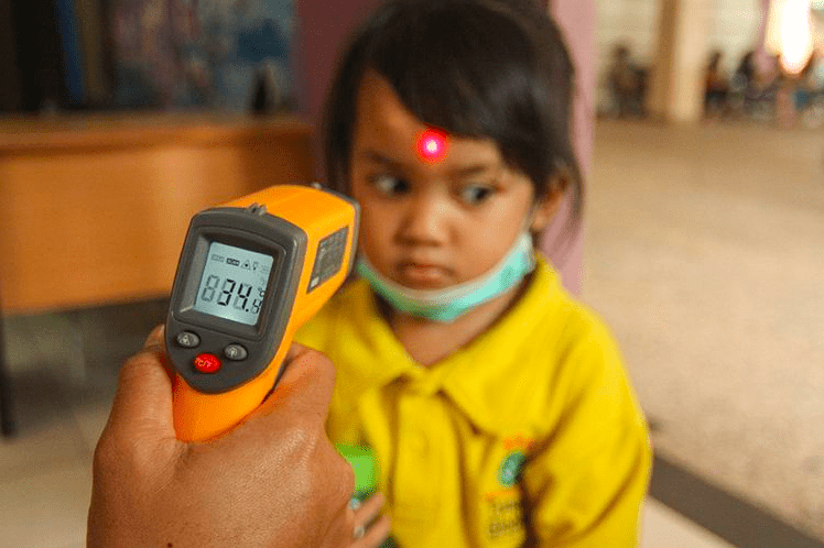 TEMBAK: Seorang bocah sedang dicek suhu tubuhnya dengan termometer tembak. (Foto: Istimewa)