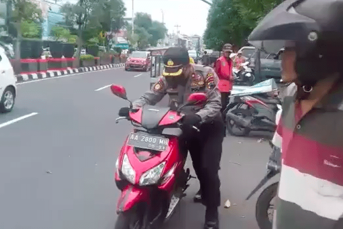 DORONG: Kapolsek Magelang Selatan Kompol M Choirul Anwar mendorong motor pengendara yang mogok. (Foto: sc instagram @polsekmagelangselatan)