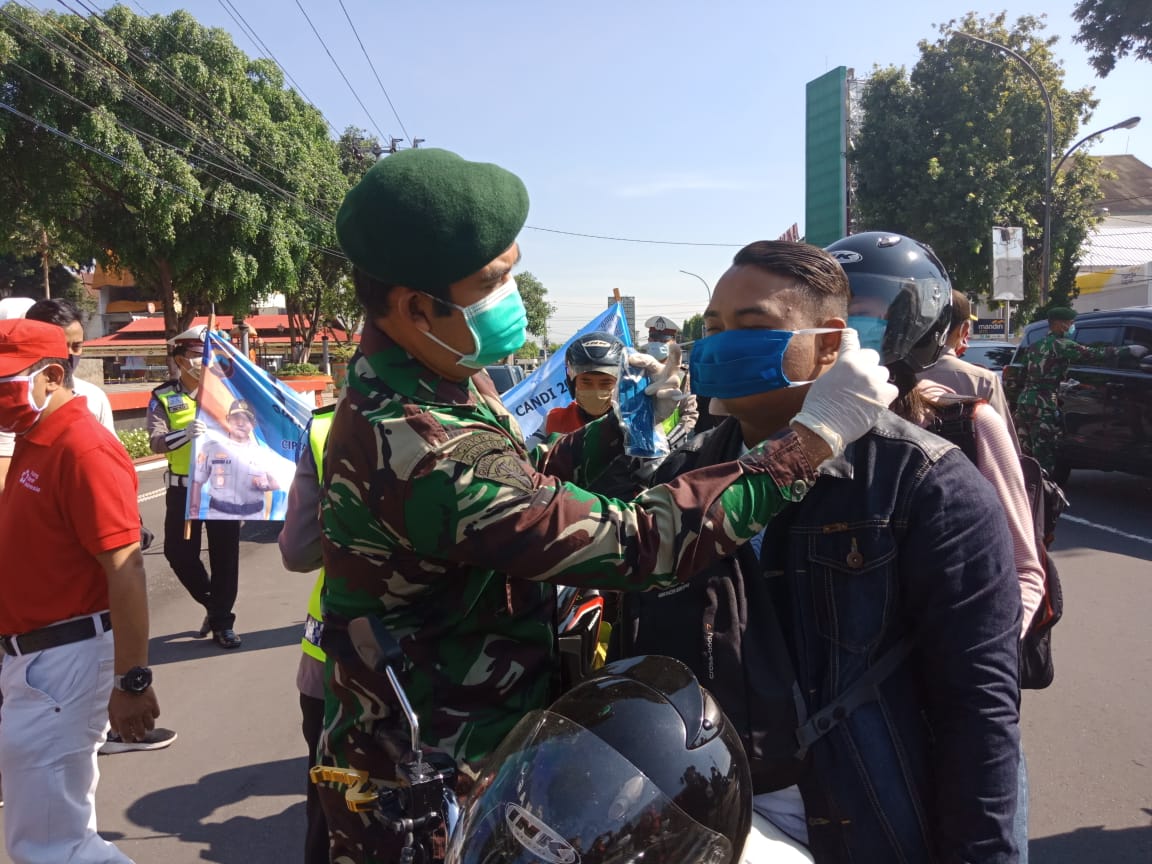 OPERASI: Prajurit Yonarmed 11 membagikan masker gratis bagi pengendara yang melintas di depan Alun-alun Magelang, Sabtu (18/4). (Foto: mta)