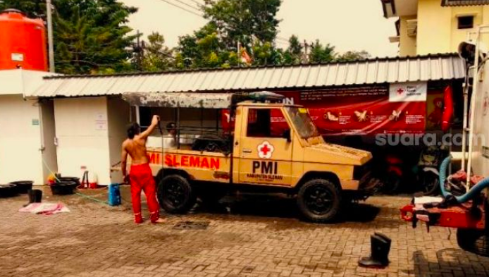 KUNO: Relawan sedang membersihkan mobil jenis kijang warna coklat di kantor PMI Sleman. (Sumber: suara.com)