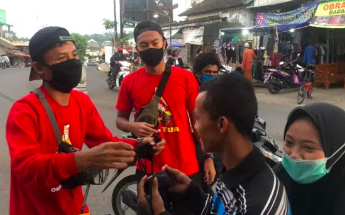 BERBAGI: Striker muda Persikabo Bogor Gustur Cahyo Putro bersama komunitas sepeda Seliweran Folding Bike membagikan masker gratis kepada masyarakat Grabag, Minggu (18/5). (Foto: istimewa)