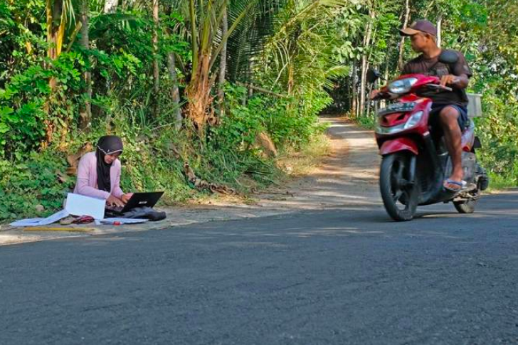 BELAJAR: Mahasiswi UM Magelang, Teara Noviani mengerjakan Ujian Tengah Semester secara daring di pinggir jalan. (Foto: antara/anis efizudin)