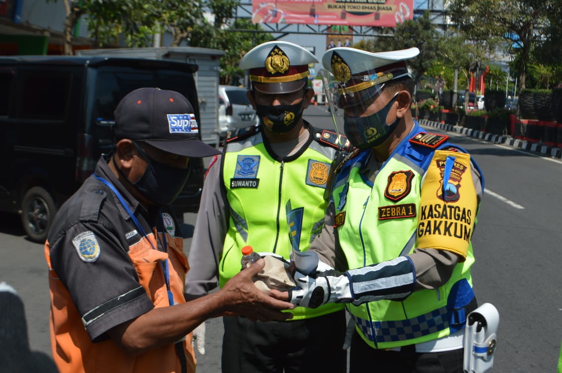 BERBAGI: Kasat Lantas AKP Sugito membagikan nasi kepada juru parkir, Senin (27/7). (Foto: istimewa)