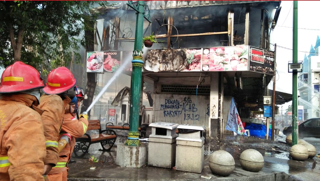 petugas damkar saat memadamkan api di cafe legian jogja saat demo yang ricuh