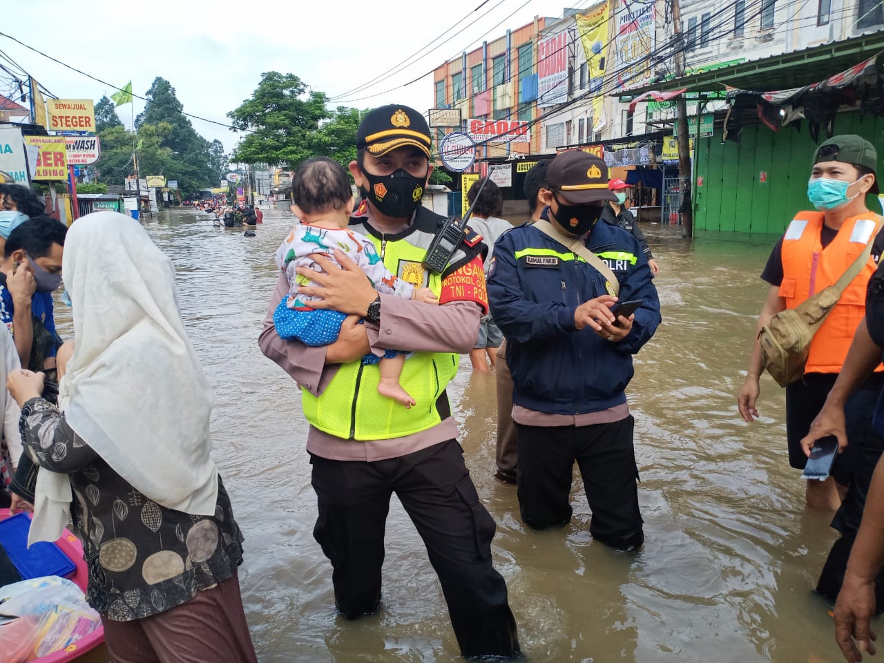 Salah satu anggota Polri saat mengevakuasi seorang anak korban banjir
