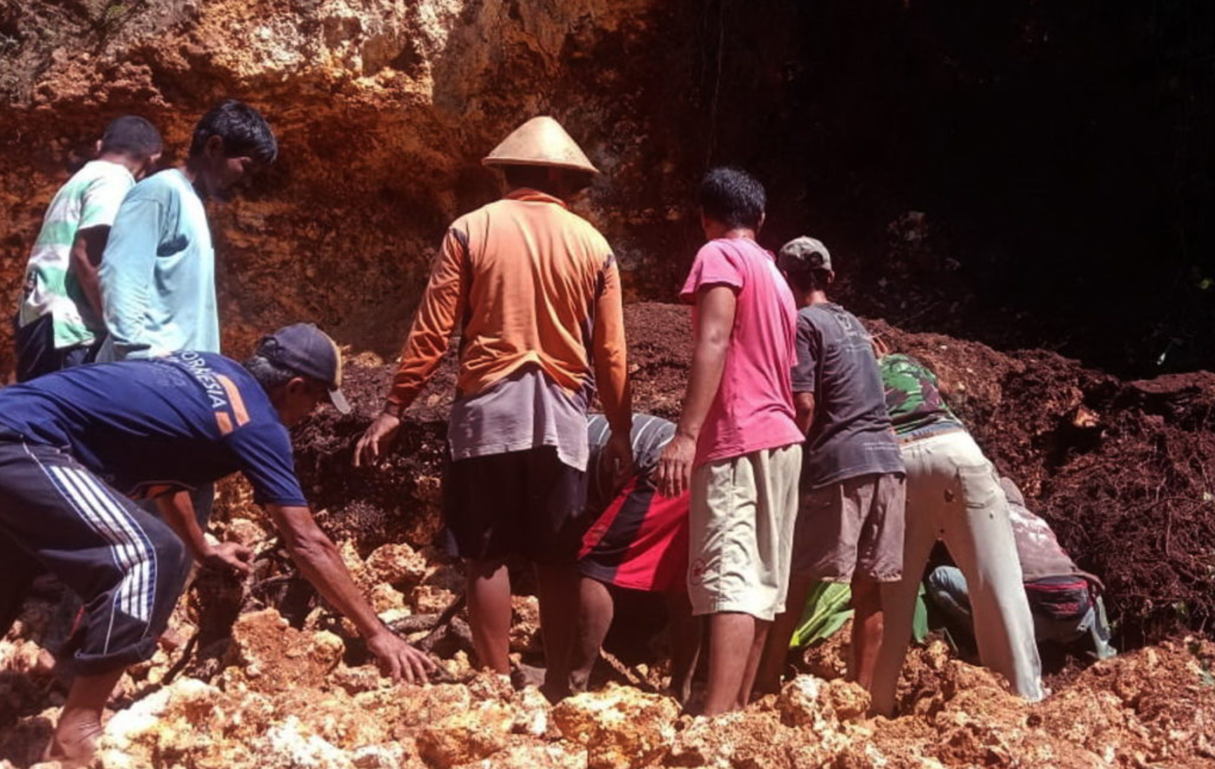 EVAKUASI: Warga berusaha mengevakuasi korban tertimbun tebing longsor dengan alat manual. (foto: ist)