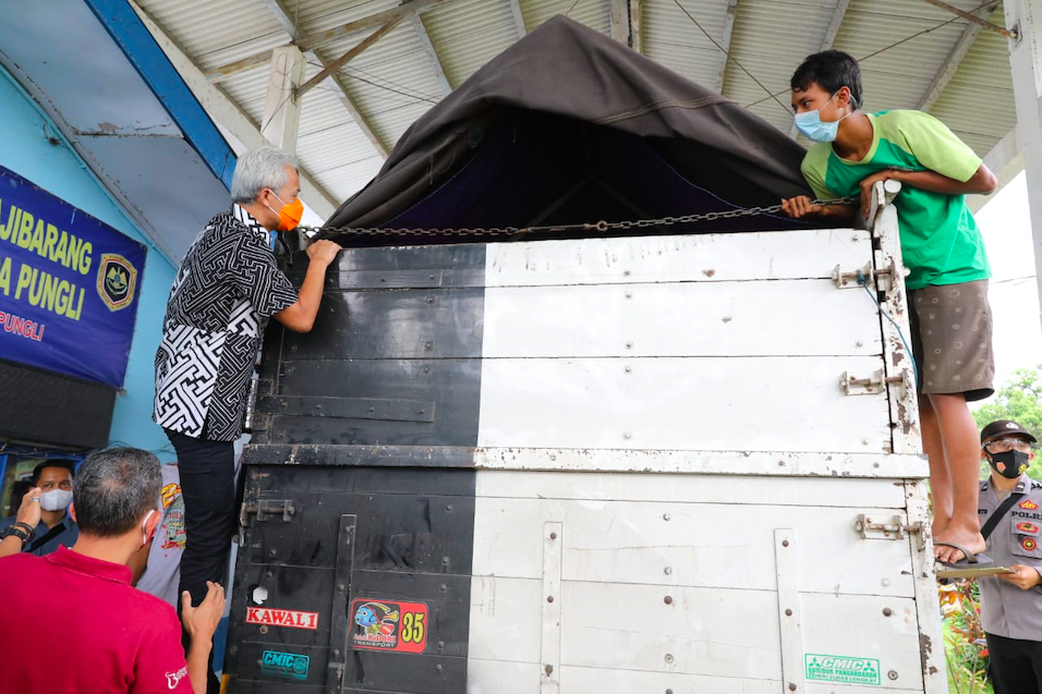 PANJAT: Gubernur Ganjar memanjat bak truk memastikan isi muatan barang tidak disusupi pemudik yang marak kucing-kucingan dengan petugas, Jumat (7/5). (foto: humas pemprov jateng)