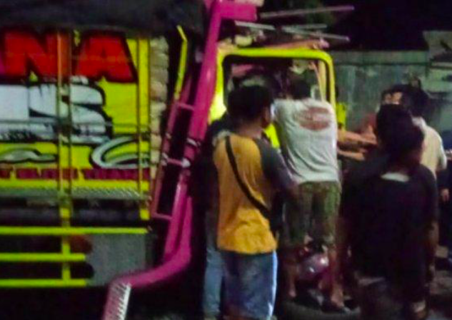 LAKA: Warga membantu mengevakuasi korban yang terjepit bodi truk. (foto: ist)