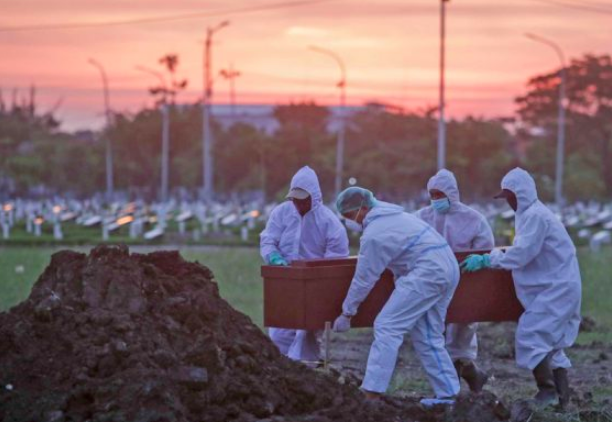Petugas pemakaman mengubur jenazah pasien positif Covid-19 secara protokol kesehatan. (foto: ist)