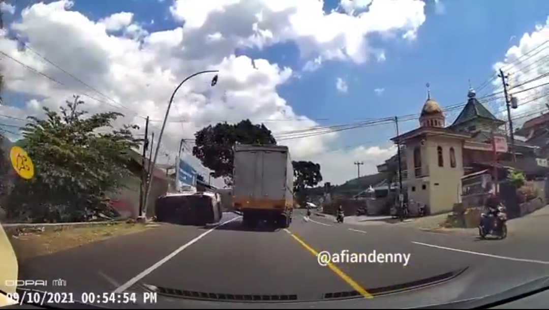 GAGAL: Sebuah mobil sedan terguling saat mencoba menyalip truk tronton dari sisi kiri. (sumber: Instagram/afiandenny)