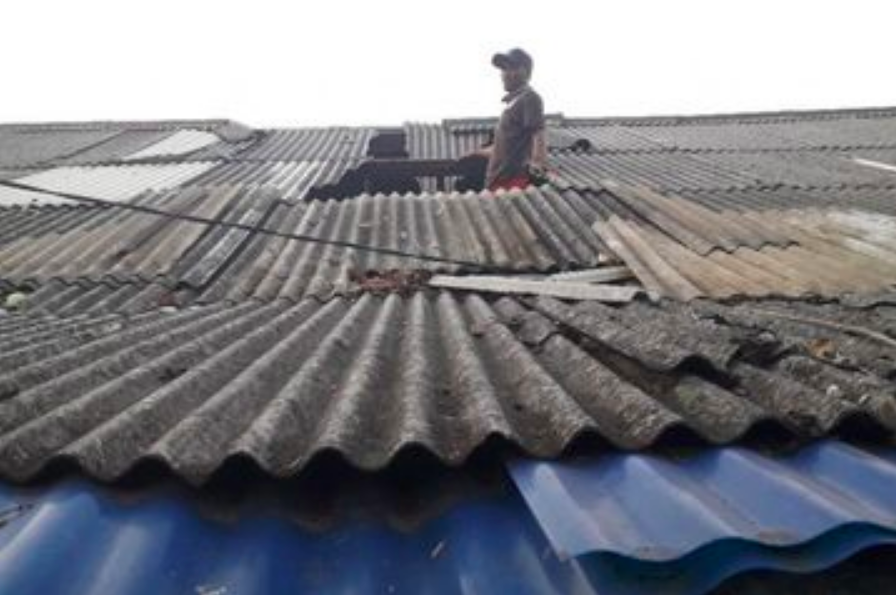 RAPUH: Ilustrasi warga memperbaiki atap rumah terbuat dari asbes. (foto: ist)