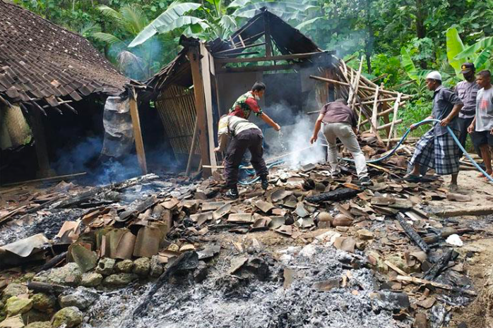 Petugas dibantu warga melakukan pendinginan di lokasi kebakaran rumah. (foto: polsek sentolo)
