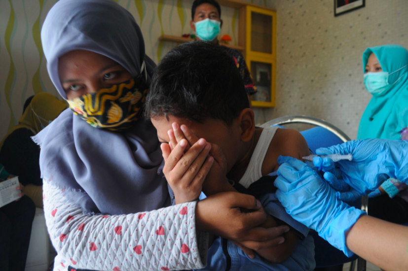 JANGAN TAKUT: Seorang bocah rentang usia 6-11 tahun menjalani vaksinasi. (foto: ist)