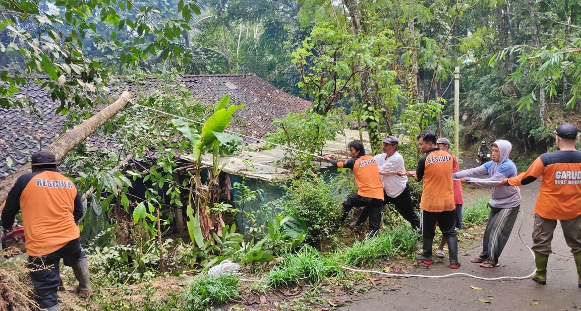 Relawan dan warga bahu membahu membantu membersihkan pohon yang tumbang menimpa rumah akibat hujan deras disertai angin di Salaman