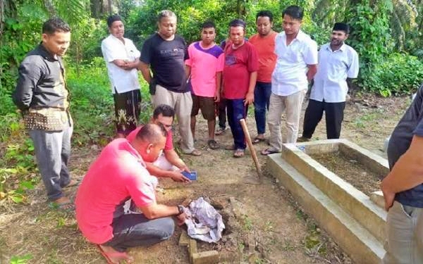 Petugas kepolisian saat mengecek makan bayi yang tali pocongnya hilang