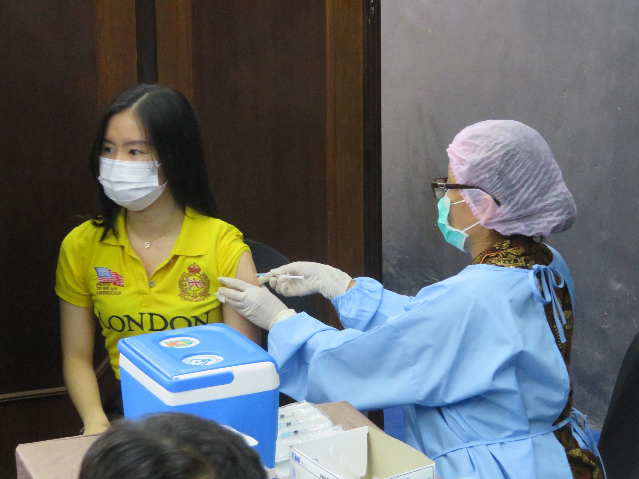 Seorang peserta sedang divaksinasi oleh petugas kesehatan.