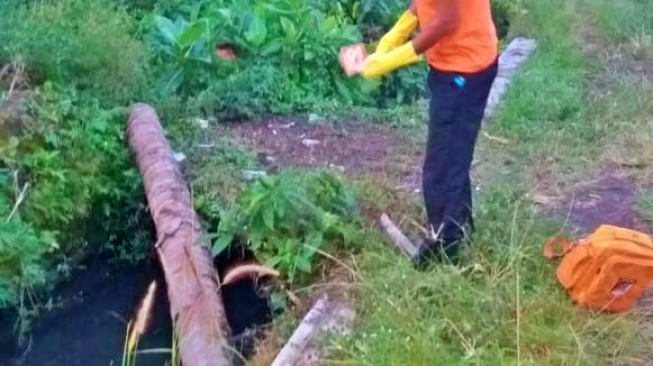 Petugas saat mengevakuasi mayat bayi laki laki yang membusuk di sungai