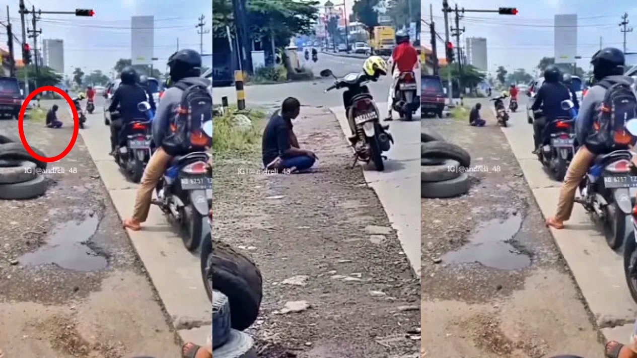 Seorang pengendara motor sholat di pinggir jalan
