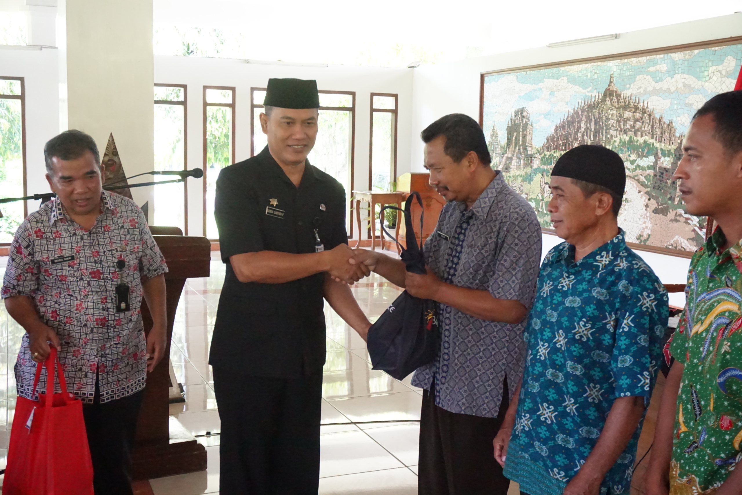 Asisten Perekonomian dan Pembangunan Setda Kabupaten Magelang, Nanda Cahyadi Pribadi didampingi Kepala Dinas Perdagangan Koperasi dan UKM Kabupaten Magelang, Basirul Hakim saat menyerahkan bantuan paket sembako kepada masyarakat pra sejahtera.