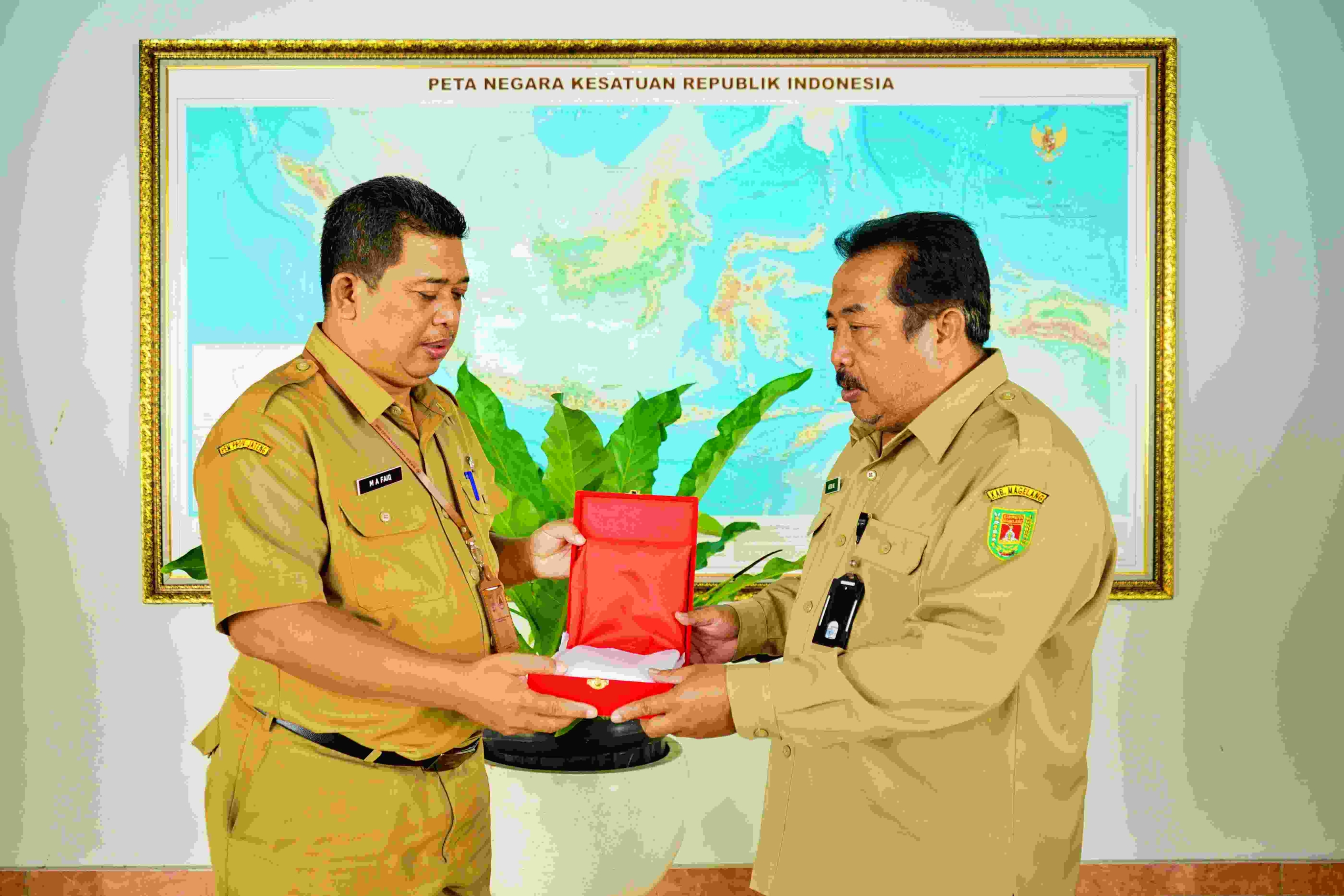 Asisten Administrasi Umum Setda Kabupaten Magelang, Asfuri Muhsis saat menyerahkan bendera Merah Putih secara simbolis kepada Sekretaris Badan Kesbangpol Kabupaten Magelang, Muhammad Faiq