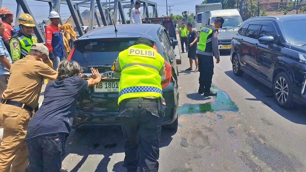 Petugas Polisi dibantu warga saat mendorong mobil yang terlibat kecelakaan di Jembatan Pabelan Magelang